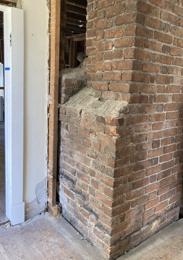 Exterior view of 18th-century brick fireplace/chimney with weathered bricks and mortar.